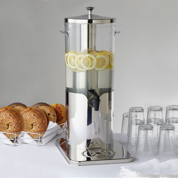 An American Metalcraft plastic juice dispenser filled with lemons and a tray of bagels.