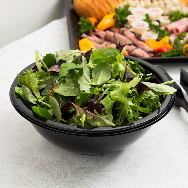A bowl of salad with green leaves in a black Fineline plastic bowl.