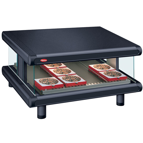 A black rectangular countertop with a slanted shelf holding pizzas in a glass oven.
