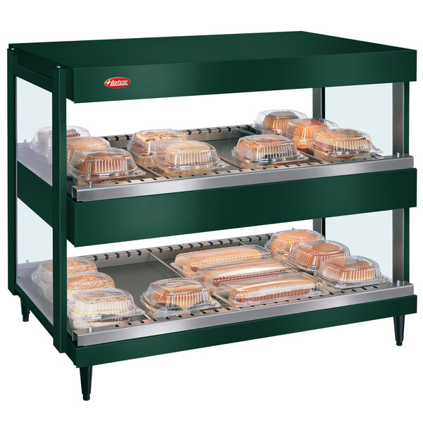 A Hatco Hunter Green countertop display warmer with food trays on shelves.