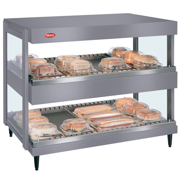 A Hatco countertop merchandiser with food trays on shelves.