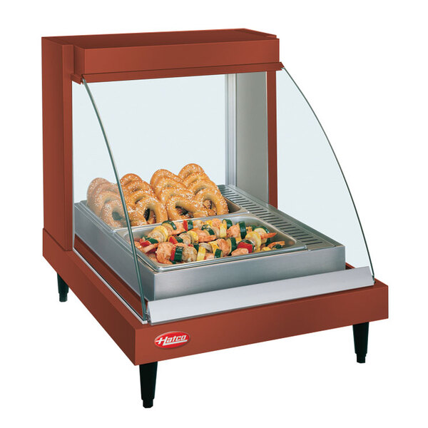 A Hatco copper countertop food warmer with pretzels and vegetables on a tray.
