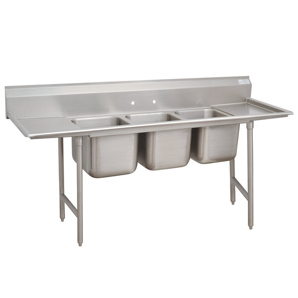 An Advance Tabco Regaline stainless steel sink with three compartments and two drainboards.