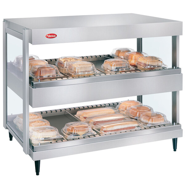 A Hatco white granite countertop with double shelves holding food trays.