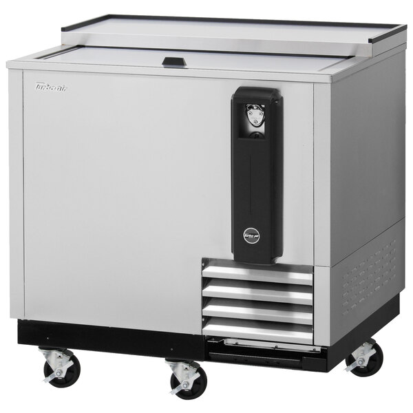 A Turbo Air stainless steel bottle cooler with a glass door on wheels.