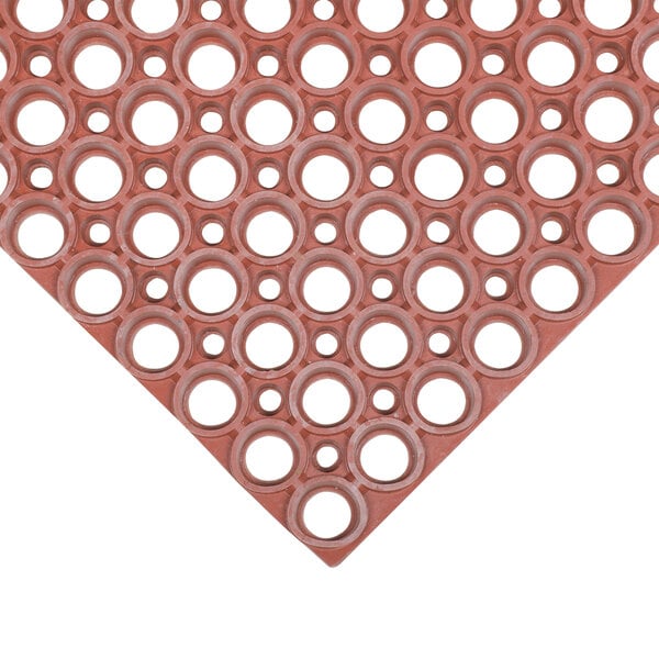 A red Notrax rubber kitchen mat with holes in it.