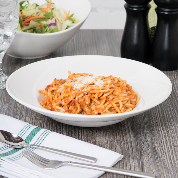 A bowl of spaghetti with cheese and a salad in a Tuxton Pearl White bowl.