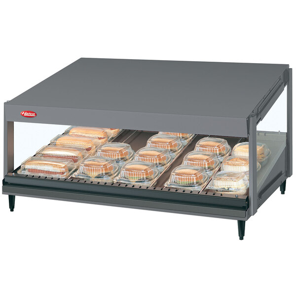 A Hatco countertop display case with food on a slanted shelf.