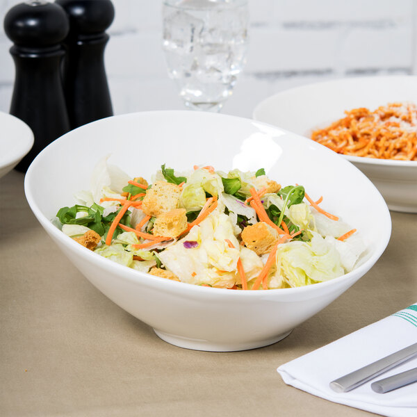 A Tuxton AlumaTux Pearl White slant bowl filled with salad with croutons and carrots.