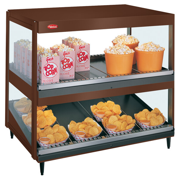 A large display case with popcorn and potato chips in a Hatco countertop hot food display warmer.
