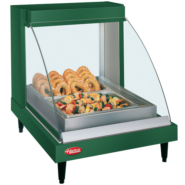 A green Hatco countertop food display case with food on a shelf.