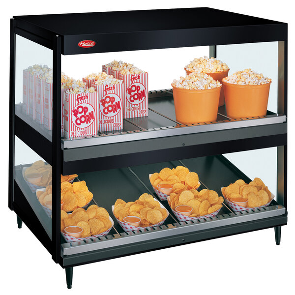A black Hatco countertop display case with popcorn and chips on double shelves.