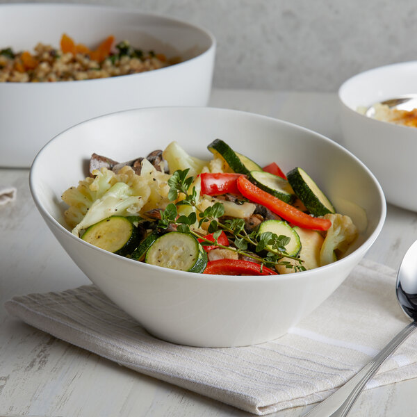 A bowl of vegetables in a Tuxton AlumaTux Pearl White bowl on a table.