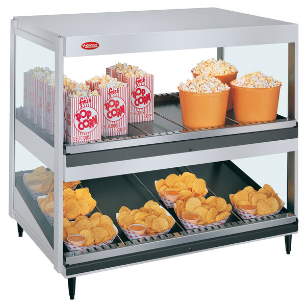 A Hatco countertop food warmer with a bowl of potato chips and a bucket of popcorn on it.