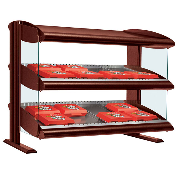 A Hatco Antique Copper LED slanted shelf merchandiser on a counter with red boxes.