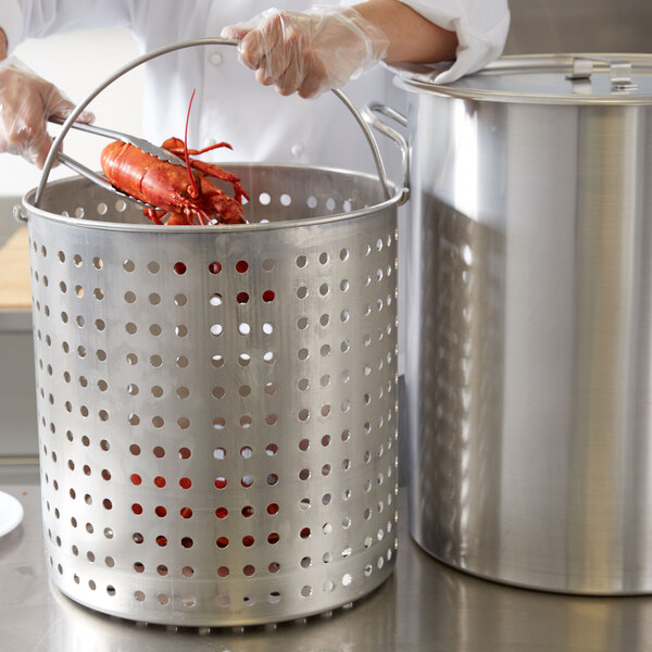 A person using a Vollrath Wear-Ever fryer pot to cook a lobster.