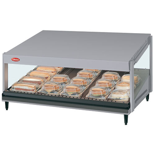A Hatco White Granite Glo-Ray slanted shelf food warmer on a counter with trays of food.