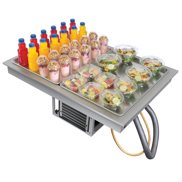 A table with a Hatco Two Pan Drop In Frost Top holding food and drinks in containers.