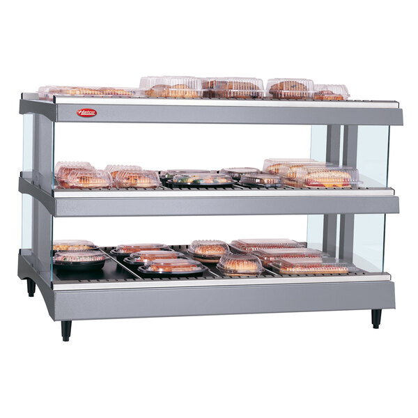 A Hatco countertop heated glass merchandising warmer with shelves of food.