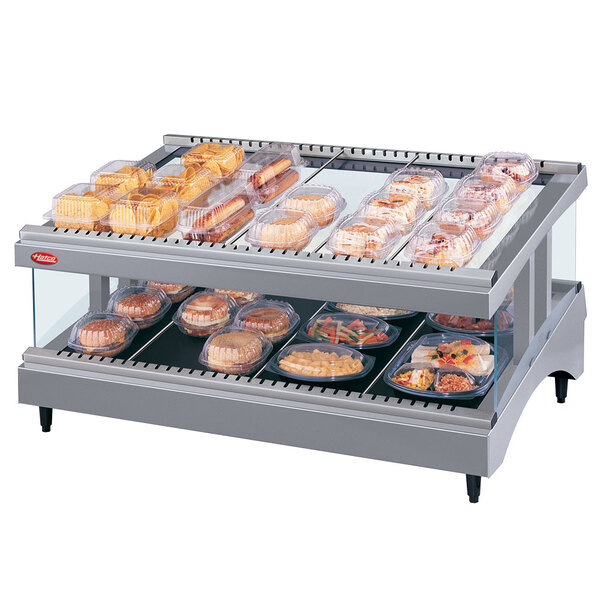 A Hatco heated glass display shelf with food on trays.
