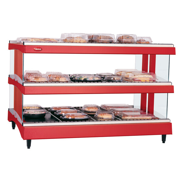 A red Hatco countertop heated glass merchandising warmer with shelves of food.