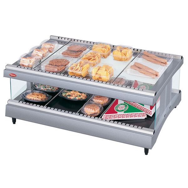 A Hatco heated glass display case on a counter with food trays inside.