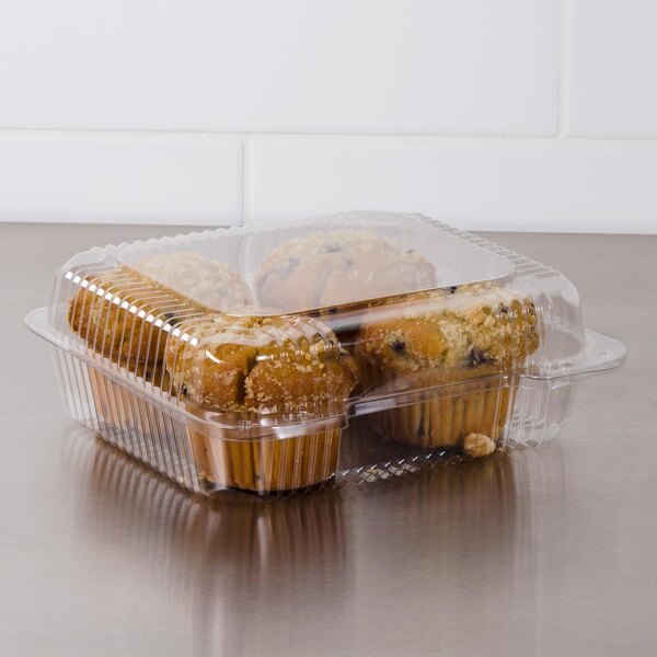 A Dart clear hinged plastic container with muffins inside.