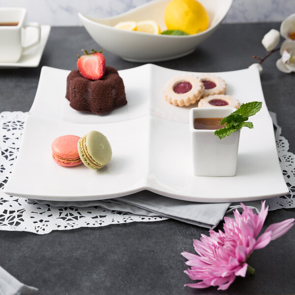 A white porcelain tapas tray with a macaroon, cookie, and lemon dessert on it.