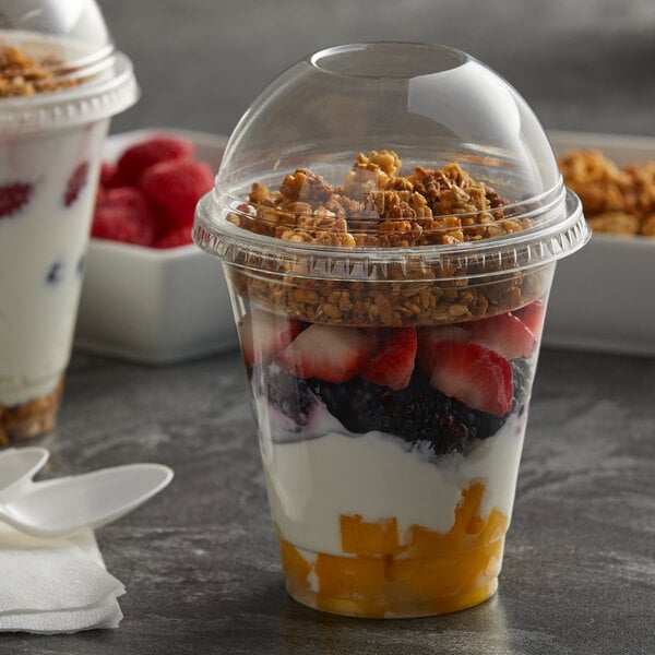A 12 oz. plastic parfait cup with Fabri-Kal insert and dome lid filled with yogurt, fruit, and granola.