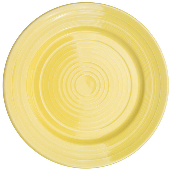 A yellow porcelain plate with a sunflower design in the center and a spiral pattern around the edge.