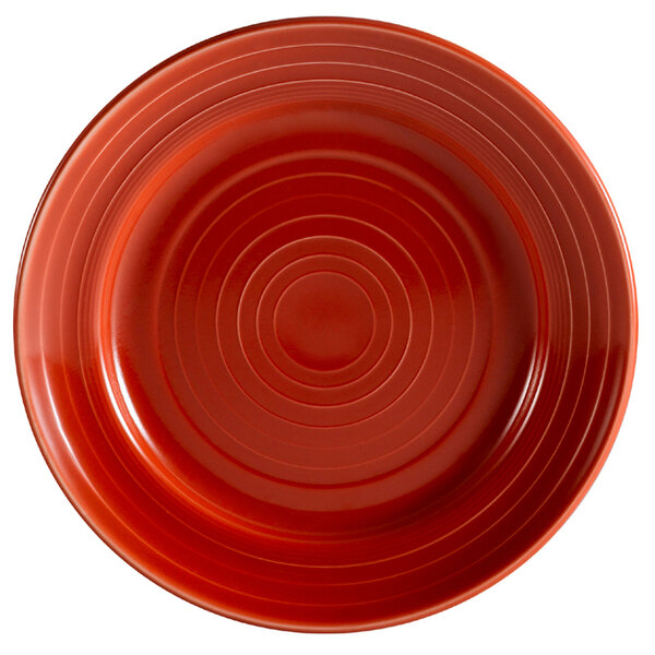 A red porcelain plate with a spiral pattern on it.