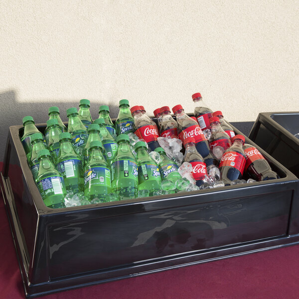 A black Geneva insulated beverage bin on a table with soda bottles and ice.