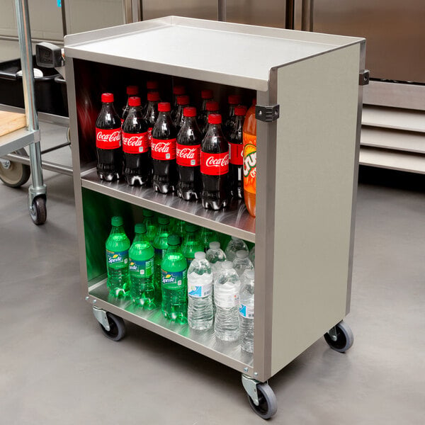 A Lakeside metal utility cart with bottles of soda and water on wheels.