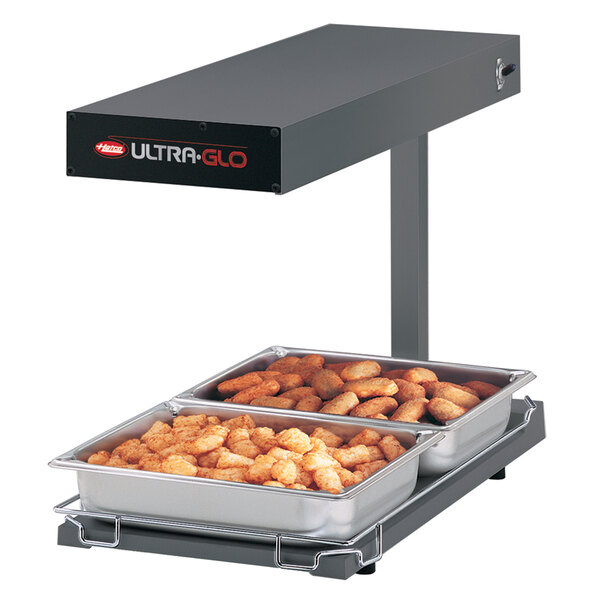 A Hatco Ultra-Glo portable food warmer holding trays of food on a counter.