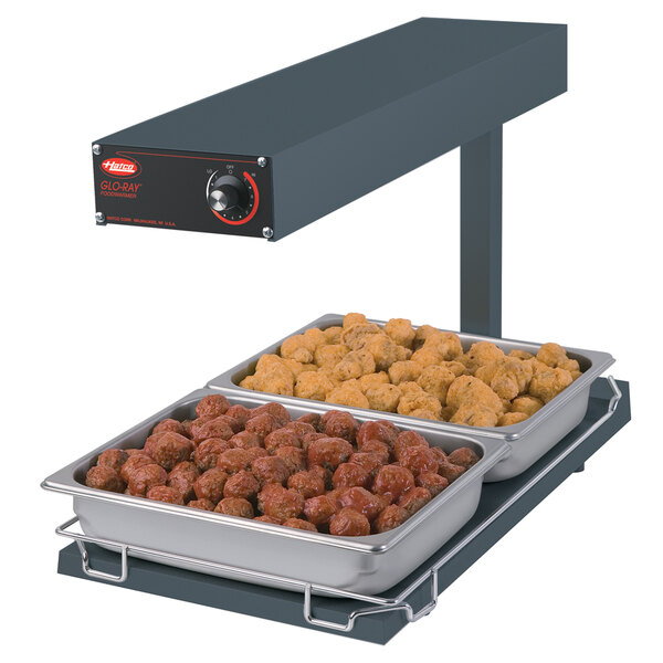 A Hatco portable food warmer with trays of meatballs and chicken on a counter.