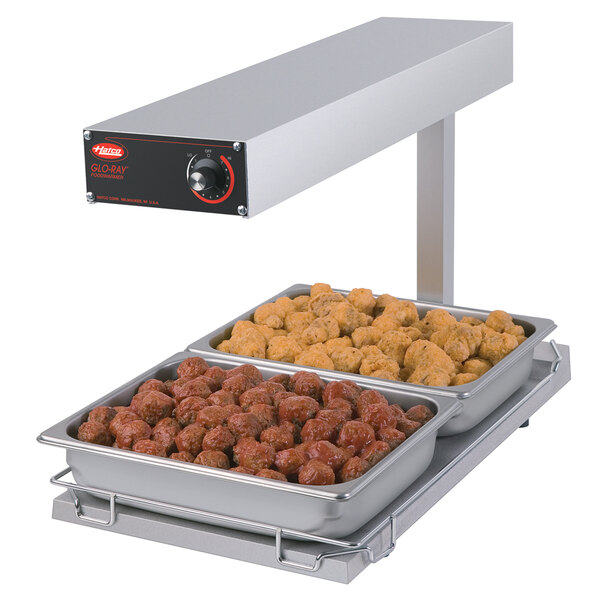 A Hatco portable food warmer with two trays of food on a heated shelf.