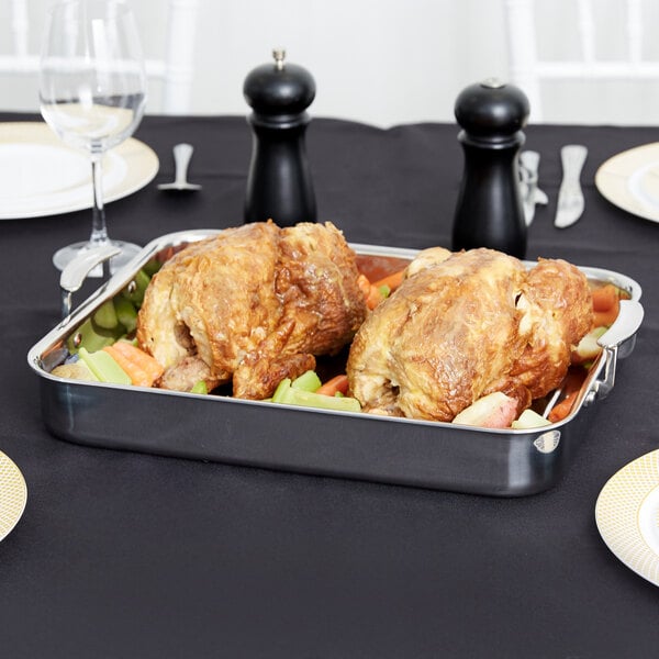 A Vollrath stainless steel roasting pan with two turkeys on a table.