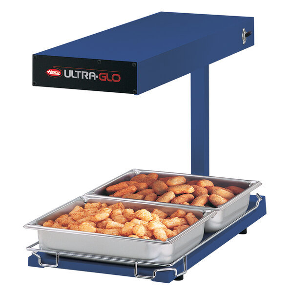 A blue Hatco Ultra-Glo food warmer heating food on a table.