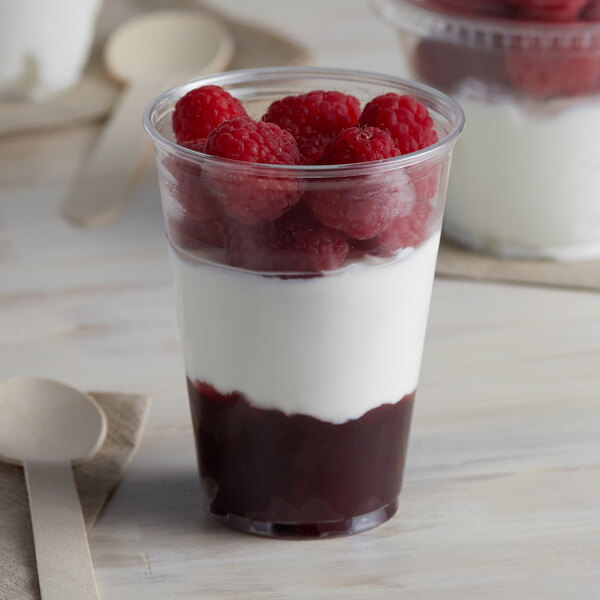 A Solo Ultra Clear plastic cup filled with raspberries and yogurt.