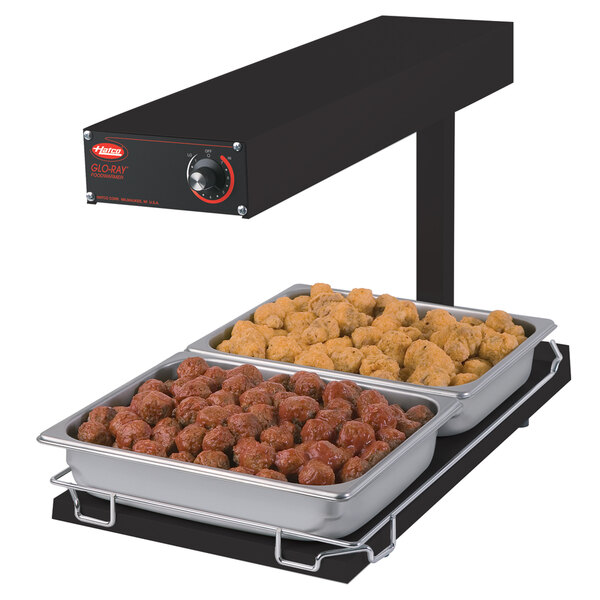 A Hatco heated food warmer on a table with two trays of food.