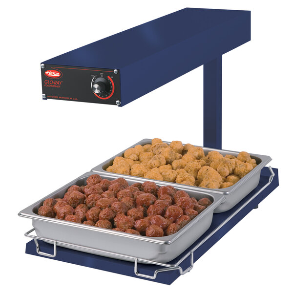 A blue Hatco food warmer with trays of meatballs and chicken on a table.
