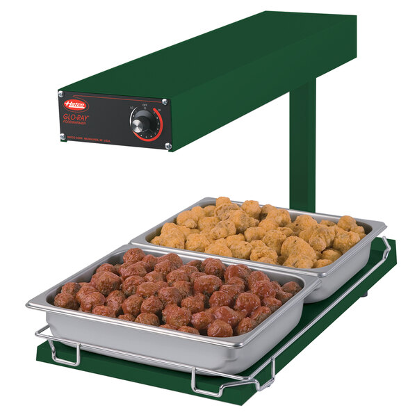 A Hatco portable food warmer with trays of meatballs and chicken on a table.