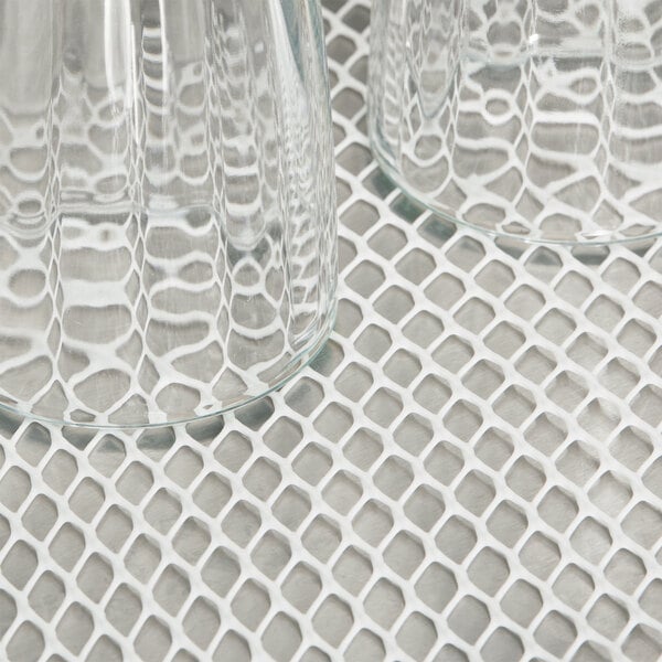 A pair of clear glasses on a white San Jamar shelf liner.