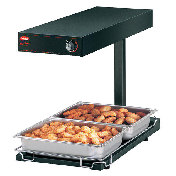 A Hatco heated food warmer on a counter with trays of tater tots.
