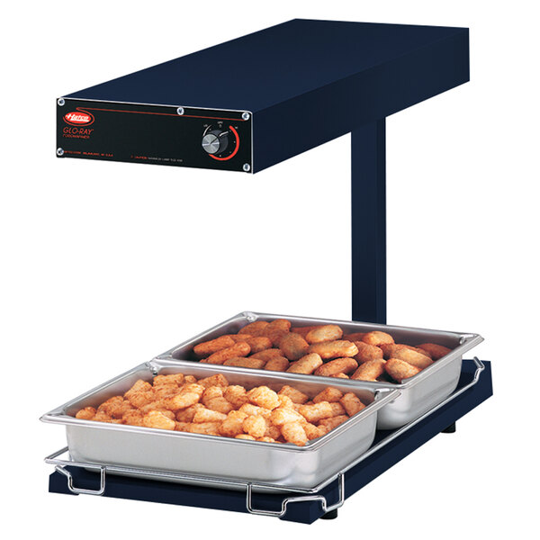 A Hatco navy heated food warmer with trays of food on it.