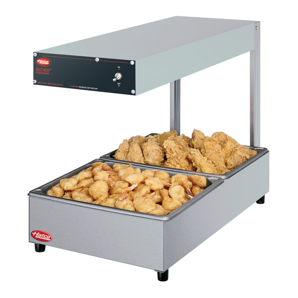 A white Hatco Glo-Ray food warmer on a counter with two large trays of food.