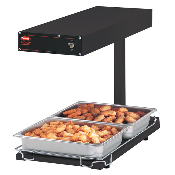A Hatco heated food warmer with trays of food on it.