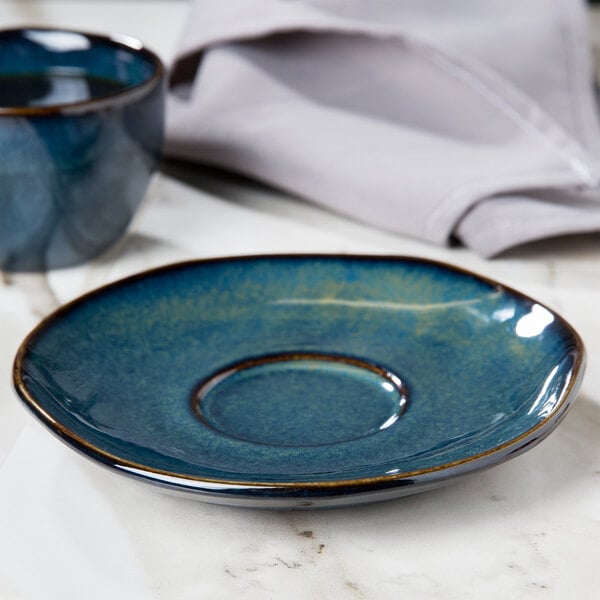A blue Tuxton saucer with a round center on a marble surface.