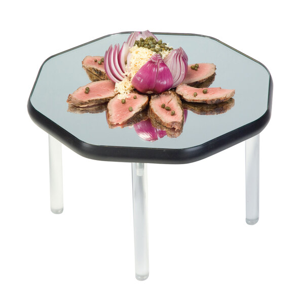 A Geneva rimless mirror food display tray with meat and green peas on a table.