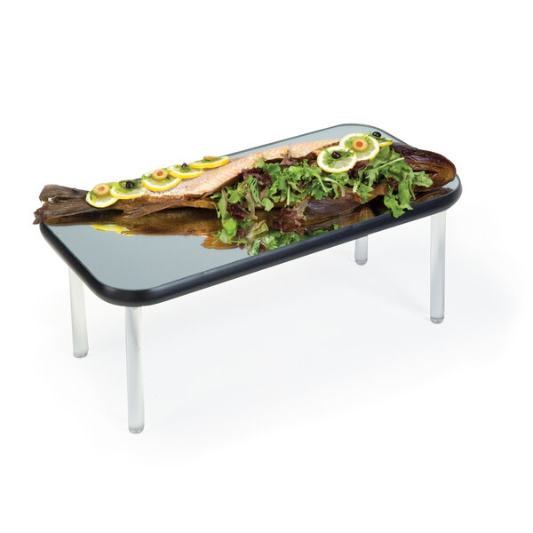 A rectangular mirror food display tray with a fish and lemons on top of it.